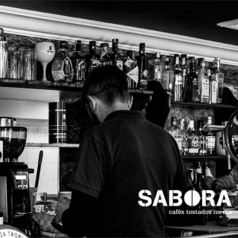 Barra de cafetería española con barista trabajando  en máquina de expreso.